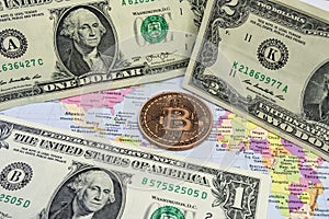 Close up physical bitcoin coin with US dollars and world map.