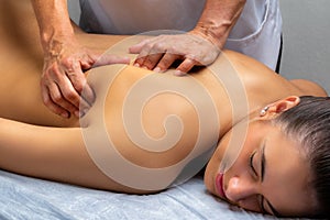 Physiotherapist manipulating shoulder blade on young woman