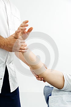 Close-up of a physiotherapist treating a patient. Osteopath holds a man& x27;s hand