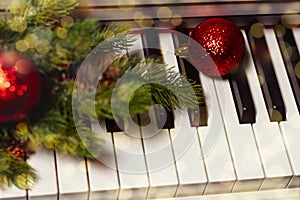 close-up of piano with a branch of a Christmas tree, pine cones and red Christmas balls on golden bokeh background.New
