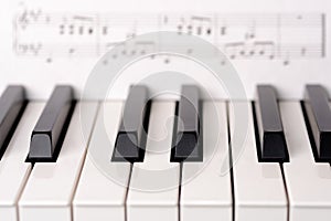 Close-up piano keyboard. Sheet music on background is copyright free