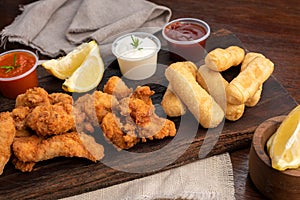 Close-up of a picada board with nuggets and tequenos with lemon slices and white and spicy sauces