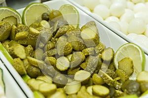 Close-up of pickled cucumber chopped into pieces in a white ceramic bowl