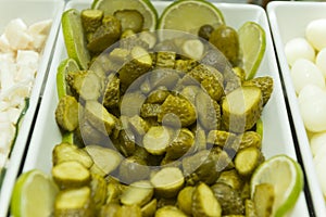 Close-up of pickled cucumber chopped into pieces in a white ceramic bowl