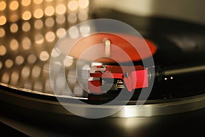 close-up of pickup head on vinyl record, color illumination, analogue retro music concept, hobby of collecting vinyl music discs,