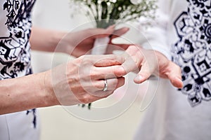 Close up picture of bride and groom`s hands putting on a wedding ring at official marriage ceremony. Bride and groom are getting