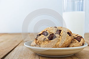 Close up picture of chocolate cookies and a cup of milk on table