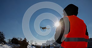 Close up picture of flaying quadrocopter dron and pilot siluette in sunset light and blue sky background, Man flying a drone in