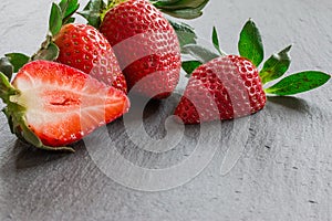 Close up picture of fresh red strawberries lying on a black stone table