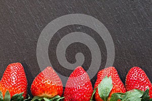 Close up picture of fresh red strawberries lying on a black stone table