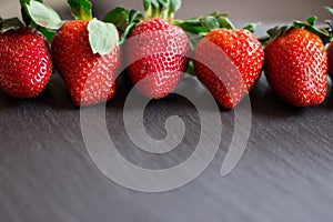 Close up picture of fresh red strawberries lying on a black stone table