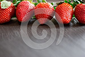 Close up picture of fresh red strawberries lying on a black stone table