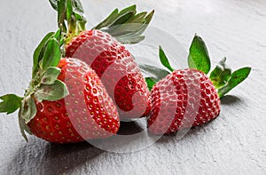 Close up picture of fresh red strawberries lying on a black stone table