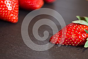 Close up picture of fresh red strawberries lying on a black stone table