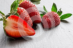 Close up picture of fresh red strawberries lying on a black stone table