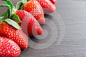 Close up picture of fresh red strawberries lying on a black stone table