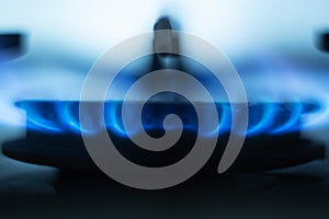 Close up picture of gas hob burning, bright blue flames situated around metallic special round in gas cooker, having light blue