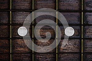 Close-up picture of a guitar with a fingerboard made of wood with a white inlay and a very old guitar string