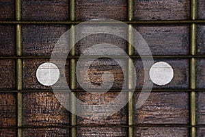 Close-up picture of a guitar with a fingerboard made of wood with a white inlay and a very old guitar string