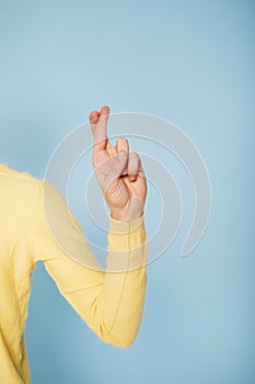 Close up picture of lucky man holds fingers together, good luck concept, hope for something over blue background