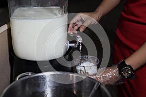 Close-up picture of a man holding a glass pressing the milk into the lon of fresh milk.