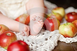 Close up picture of new born baby feet on knitted plaid and apples