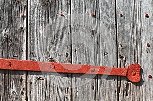 Close up picture of an old wooden door with rusty lock bar