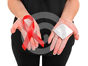 Red ribbon and a condom on female hands isolated on a white background. AIDS Awareness. Healthcare and medicine concept.