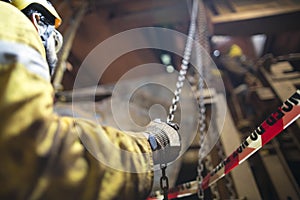 Rigger wearing helmet safety glass using hand commencing pulling a heavy duty chains block photo