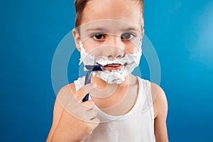 Close up picture of Smiling Young boy trying shaving face