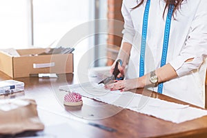 Close-up picture of tailor s hands cutting cloth with scissors on table in sewing workshop.