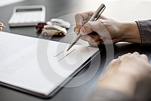 A close-up picture of the tenant who is about to sign the signature on the car rental contract.