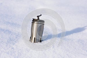 Close up picture of thermos with hot coffee in snow of winter