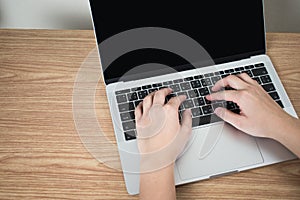 Close-up picture, top view of the hand, people are using a laptop on a brown wood table