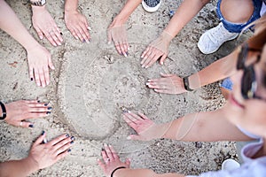 Close-up picture of women`s hands on the sand. making the form of heart. Hen party celebration on the beach