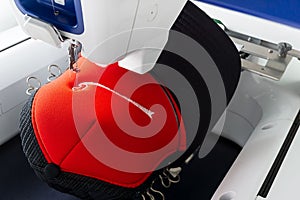 Close up picture of working embroidery machine and red cap