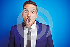 Close up picture of young handsome business man over blue isolated background afraid and shocked with surprise expression, fear