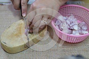 Close-up pictures of people. The chefs are slicing red onions, small vegetables, herbs on a wooden cutting board.