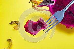 Close-up of piece of bitten pitaya, dragon fruit on fork, yellow background