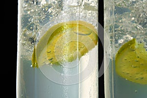 Close-up of a piece of lime with ice cubes in a glass with a mojito cocktail