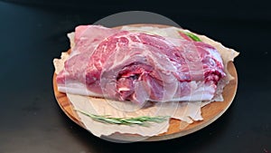 Close-up. A piece of raw fresh meat rotates on a plate on a dark background