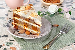 Close-up the piece of vegetarian carrot cake with almonds on a saucer and a fork near.