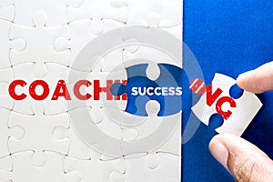 Close up piece of white jigsaw puzzle with COACHING and SUCCESS