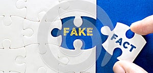 Close up a piece of white jigsaw puzzle with FACT FAKE text , concept of fake news or information