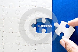 Close up piece of white jigsaw puzzle with SUCCESS text , a concept of business challenge success completion with teamwork