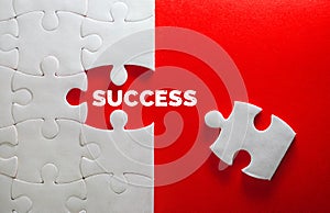 Close up piece of white jigsaw puzzle with SUCCESS text , a concept of business challenge success completion with teamwork