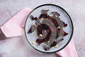 Close up of pieces of baked beets with rosemary and garlic on a plate on the table top view