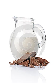 Close-up pieces of chunk black chocolate with glass jug of milk