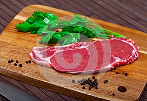 close up of pieces of striploin served with parley on wooden table