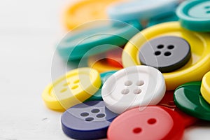 Close up of pile of colorful buttons on white background